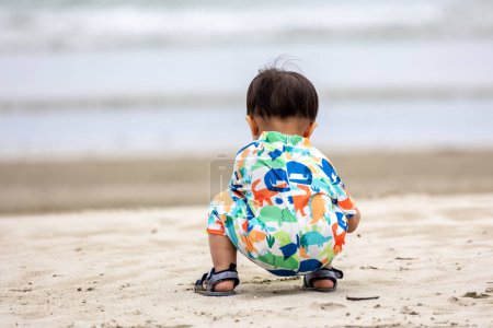 Foto de Un bebé chino asiático en la playa con los juguetes para la arena. Juegos infantiles. Juegos en la playa - Imagen libre de derechos