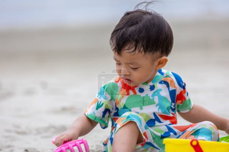Foto de Feliz niño de 1-2 años disfrutando jugando en la playa con agua tibia salpicada - Imagen libre de derechos