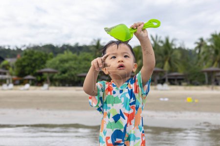 Téléchargez les photos : Heureux 1-2 ans enfant jouissant de jouer sur la plage avec des éclaboussures d'eau de mer chaude - en image libre de droit