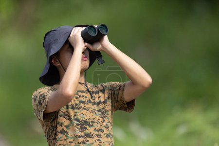 Foto de Kota Kinabalu, Sabah, Malasia-31 de mayo de 2022: Joven no identificado usando prismáticos con sombrero en busca de aves silvestres - Imagen libre de derechos