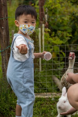 Foto de Happy Kids juega y alimenta a un conejo adorable en la granja de conejos - Imagen libre de derechos