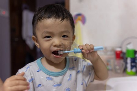 Téléchargez les photos : Un enfant avec une expression heureuse pendant les dents de brosse - en image libre de droit