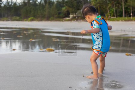 Foto de Niño chino asiático feliz jugando en la playa. El chico se divierte al aire libre. Vacaciones de verano y concepto de estilo de vida saludable - Imagen libre de derechos
