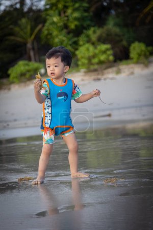 Photo for Happy Asian Chinese child playing in the beach. Kid having fun outdoors. Summer vacation and healthy lifestyle concept - Royalty Free Image