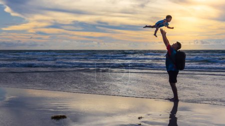Téléchargez les photos : Heureux père et fils sur la plage. Le gamin s'amuse dehors. Vacances d'été et mode de vie sain concept - en image libre de droit