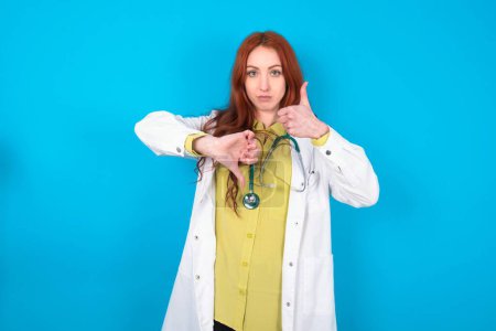 Photo for Young redhead caucasian doctor woman over blue background showing thumb up down sign - Royalty Free Image