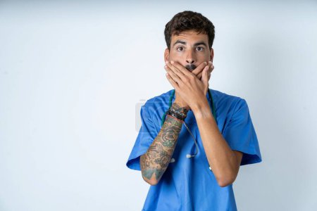 Photo for Handsome nurse man wearing surgeon uniform over white background shocked covering mouth with hands for mistake. Secret concept. - Royalty Free Image