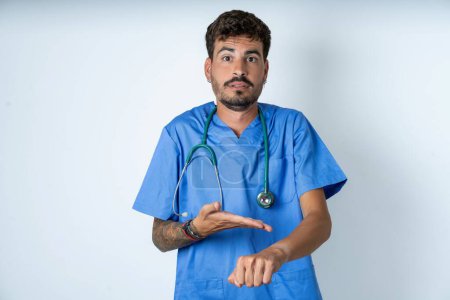 Photo for Handsome nurse man wearing surgeon uniform over white background In hurry pointing to watch time, impatience, upset and angry for deadline delay. - Royalty Free Image