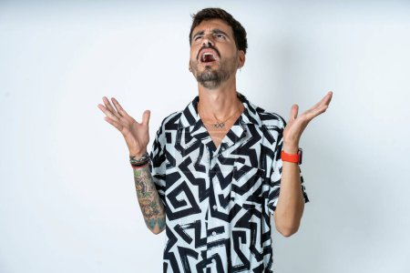 Photo for Young caucasian man wearing printed shirt crazy and mad shouting and yelling with aggressive expression and arms raised. Frustration concept. - Royalty Free Image