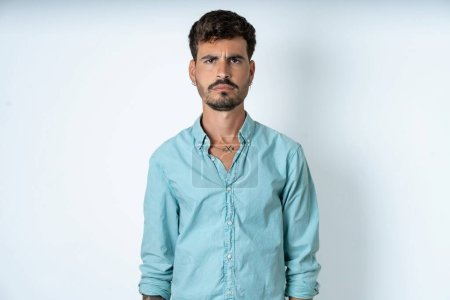 Photo for Handsome young man wearing turquoise shirt over white background Pointing down with fingers showing advertisement, surprised face and open mouth - Royalty Free Image