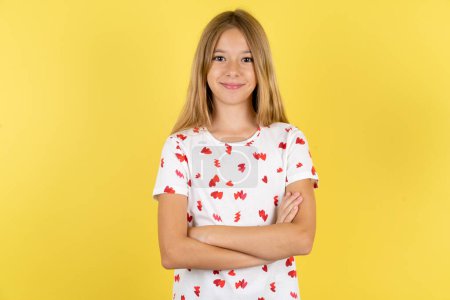 Photo for Dreamy rest relaxed caucasian kid girl wearing polka dot shirt over yellow background crossing arms, - Royalty Free Image