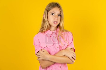 Photo for Girl wearing pink jacket over yellow background shaking and freezing for winter cold with sad and shock expression on face. - Royalty Free Image