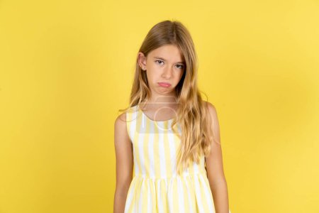 Photo for Girl wearing yellow dress over yellow background depressed and worry for distress, crying angry and afraid. Sad expression. - Royalty Free Image