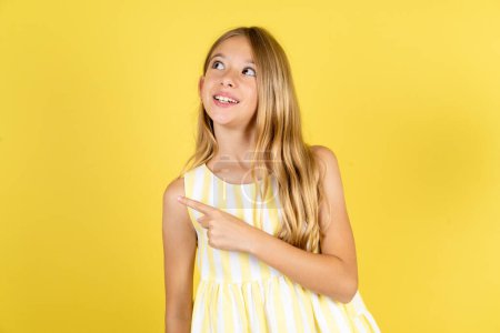 Photo for Girl wearing yellow dress over yellow background glad cheery demonstrating copy space look novelty - Royalty Free Image
