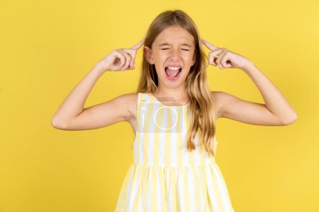 Téléchargez les photos : Photo de fille folle portant une robe jaune sur fond jaune criant et pointant des doigts vers les cheveux les yeux fermés - en image libre de droit