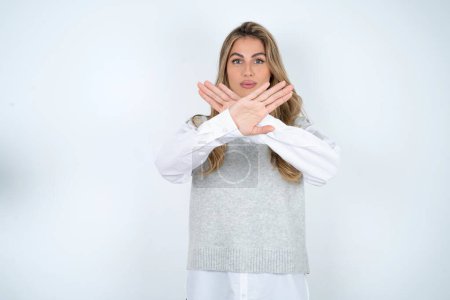 Photo for Beautiful hispanic blonde businesswoman over white background has rejection expression crossing arms and palms doing negative sign, angry face. - Royalty Free Image