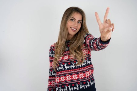 Photo for Beautiful blonde woman wearing knitted christmas sweater directs fingers at camera selects someone. I recommend you. Best choice - Royalty Free Image