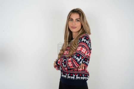 Photo for Portrait of beautiful blonde woman wearing knitted christmas sweater standing with folded arms and smiling - Royalty Free Image