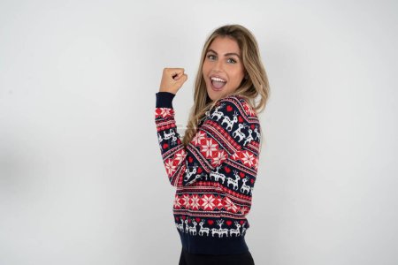Photo for Profile side view portrait beautiful blonde woman wearing knitted christmas sweater celebrates victory - Royalty Free Image