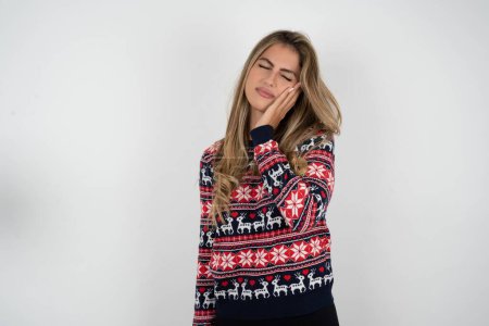 Photo for Beautiful blonde woman wearing knitted christmas sweater with toothache on white background - Royalty Free Image