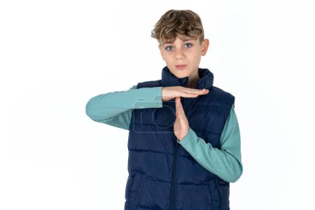 Photo for Handsome Caucasian teen boy in blue vest being upset showing a timeout gesture, needs stop, asks time for rest after hard work, - Royalty Free Image