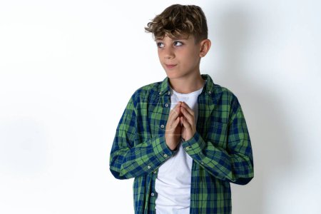 Photo for Charming cheerful handsome teen boy wearing plaid shirt over white background making up plan in mind holding hands together, setting up an idea. - Royalty Free Image