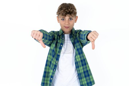 Photo for Handsome teen boy wearing plaid shirt over white background being upset showing thumb down with two hands. Dislike concept. - Royalty Free Image