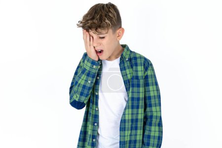 Photo for Handsome teen boy wearing plaid shirt over white background Yawning tired covering half face, eye and mouth with hand. Face hurts in pain. - Royalty Free Image