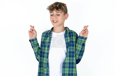 Photo for Handsome teen boy wearing plaid shirt over white background gesturing finger crossed smiling with hope and eyes closed. Luck and superstitious concept. - Royalty Free Image