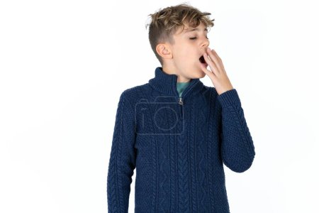 Photo for Handsome Caucasian teen boy in blue sweater being tired and yawning after spending all day at work. - Royalty Free Image