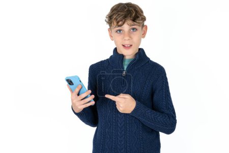 Téléchargez les photos : Beau caucasien adolescent garçon en bleu pull tenant dans les mains montrant nouvelle cellule, - en image libre de droit