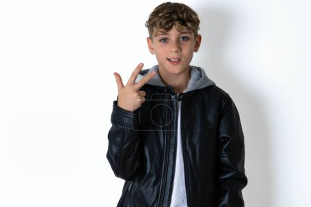 Photo for Handsome teen boy in leather jacket posing over white studio background smiling and looking friendly, showing number three or third with hand forward, counting down - Royalty Free Image
