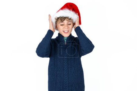 Photo for Handsome caucasian teen boy in blue sweater and christmas hat goes crazy as head goes around feels stressed because of horrible situation - Royalty Free Image