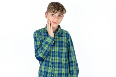 Foto de Foto de niño adolescente guapo con camisa a cuadros sobre fondo blanco disfrutar de la piel suave perfecta fresca cara táctil - Imagen libre de derechos