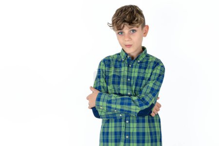 Foto de Confiado adolescente guapo con camisa a cuadros sobre fondo blanco con los brazos cruzados mirando a la cámara - Imagen libre de derechos