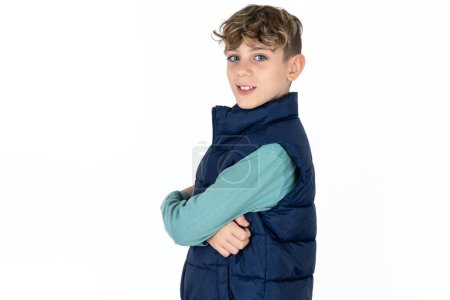 Foto de Retrato de chico adolescente caucásico guapo en chaleco azul de pie con los brazos cruzados y sonriendo - Imagen libre de derechos