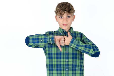 Foto de Guapo adolescente chico usando camisa a cuadros sobre fondo blanco mostrando el pulgar hacia abajo signo - Imagen libre de derechos