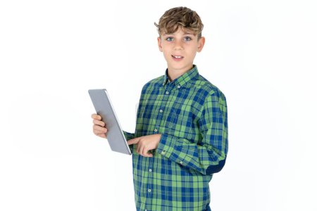 Foto de Foto de feliz alegre adolescente inteligente con camisa a cuadros sobre fondo blanco mantenga la tableta de navegación por Internet - Imagen libre de derechos