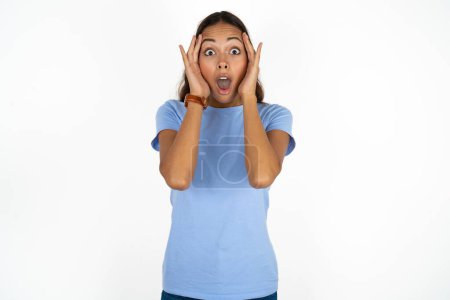 Photo for Young beautiful hispanic woman wearing blue t-shirt over white background with scared expression, keeps hands on head, jaw dropped, has terrific expression. Omg concept - Royalty Free Image