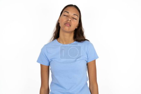 Téléchargez les photos : Jeune belle femme hispanique portant t-shirt bleu sur fond blanc regardant somnolent et fatigué, épuisé par la fatigue et la gueule de bois, les yeux paresseux le matin. - en image libre de droit