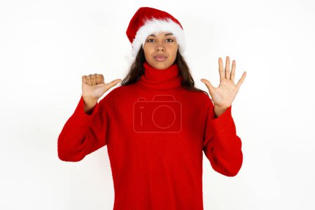 Photo for Young beautiful woman wearing red sweater and santa claus hat at christmas showing and pointing up with fingers number six while smiling confident and happy. - Royalty Free Image