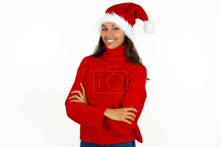 Photo for Young beautiful woman wearing red sweater and santa claus hat at christmas happy face smiling with crossed arms looking at the camera. Positive person. - Royalty Free Image