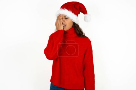 Téléchargez les photos : Jeune belle femme portant un pull rouge et santa claus chapeau à Noël bâillement fatigué couvrant demi-visage, oeil et bouche avec la main. Le visage souffre dans la douleur. - en image libre de droit