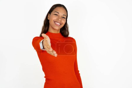 Photo for Young hispanic woman wearing red turtleneck over white background smiling friendly offering handshake as greeting and welcoming. Successful business. - Royalty Free Image