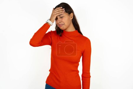 Foto de Una joven hispana muy molesta y solitaria con cuello alto rojo sobre fondo blanco llorando - Imagen libre de derechos