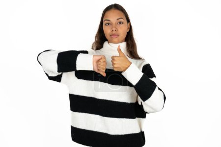 Téléchargez les photos : Jeune belle femme portant un pull rayé sur fond blanc montrant pouce vers le bas signe - en image libre de droit