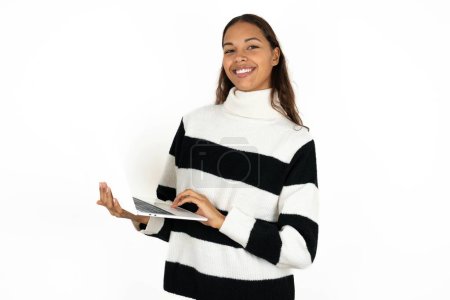 Photo for Adorable young beautiful woman wearing striped sweater on white background holding modern device - Royalty Free Image