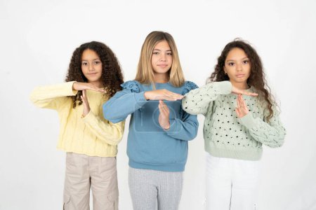 Photo for Three young beautiful multiracial kid girls being upset showing a timeout gesture, needs stop, asks time for rest after hard work, - Royalty Free Image