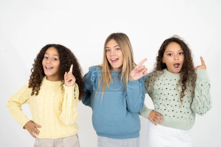 Photo for Three young beautiful multiracial kid girls holding fingers up having idea and posing - Royalty Free Image