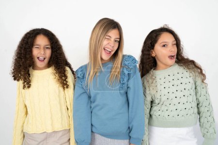 Photo for Three young beautiful multiracial kid girls winking looking at the camera with sexy expression, cheerful and happy face. - Royalty Free Image
